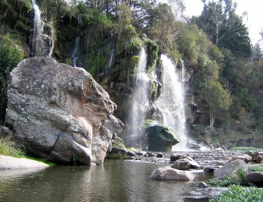 Cascada natural rodeada de piedras y vegetación en La Falda Córdoba