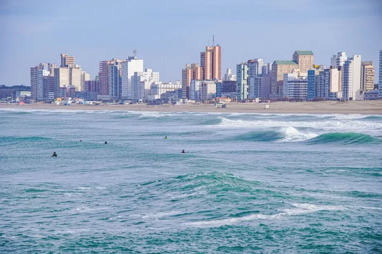 Surfistas en el mar de Necochea con vista a la ciudad al fondo
